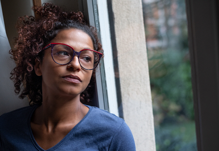 woman in glasses looking out window anxiety therapy