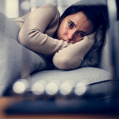 woman with head in arms on a couch