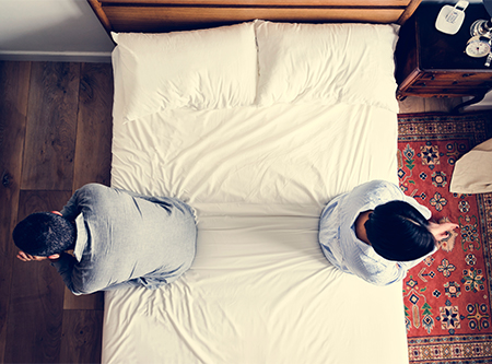 Breakup and divorce support; two people sitting on opposite sides of bed, overhead shot